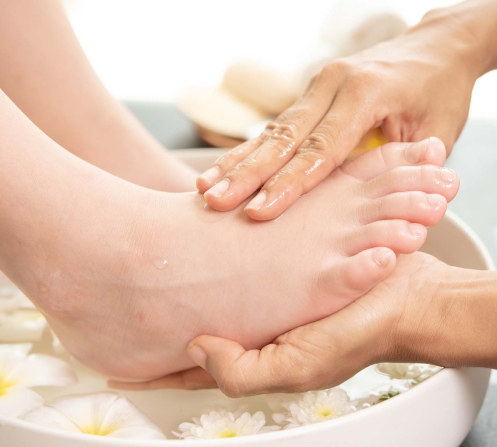 foot washing in spa before treatment. spa treatment and product for female feet and hand spa. white flowers in ceramic bowl with water for aromatherapy at spa.